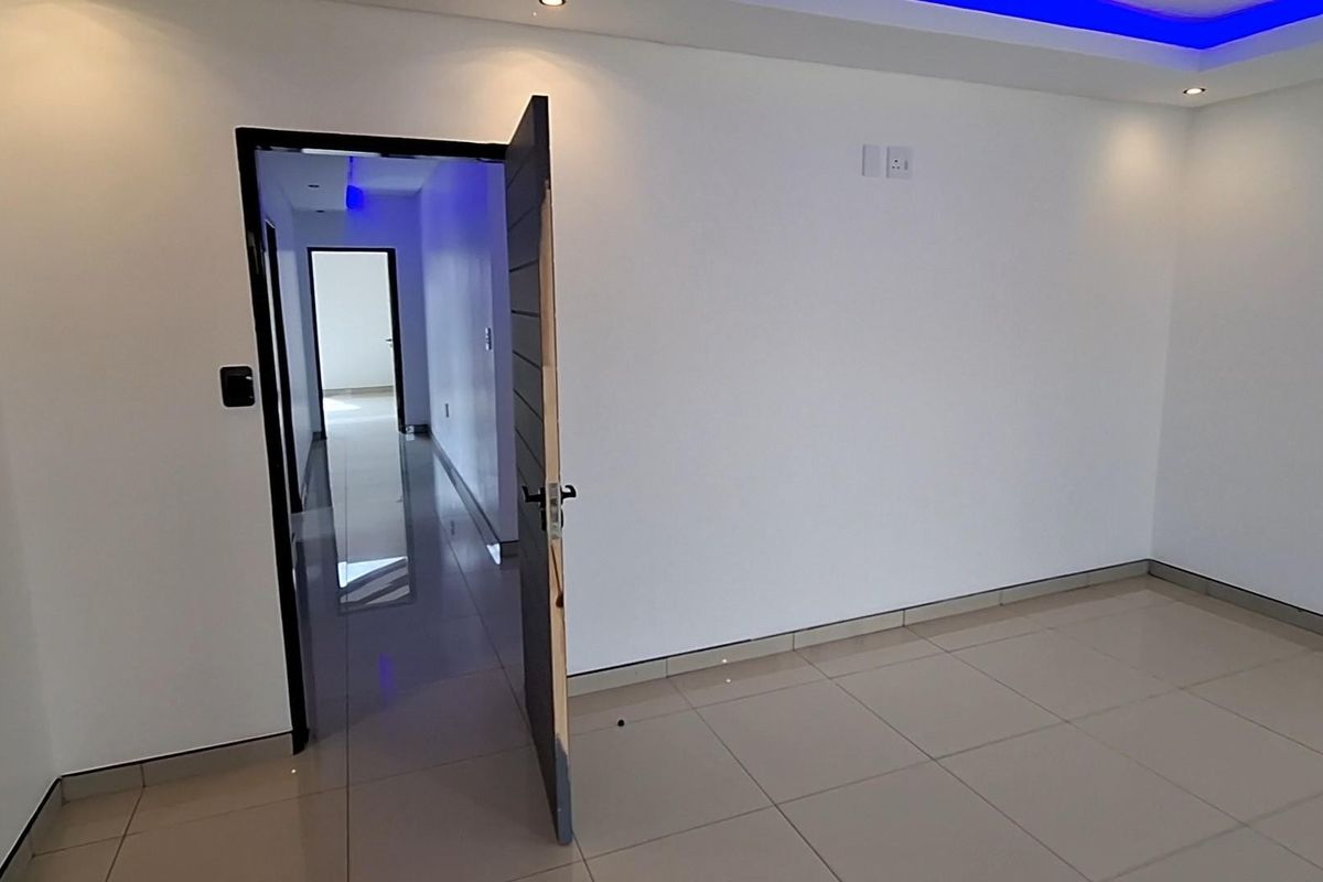 A clean, empty bedroom featuring modern tiled flooring, recessed ceiling lighting with blue accent features, and a neutral interior finish.