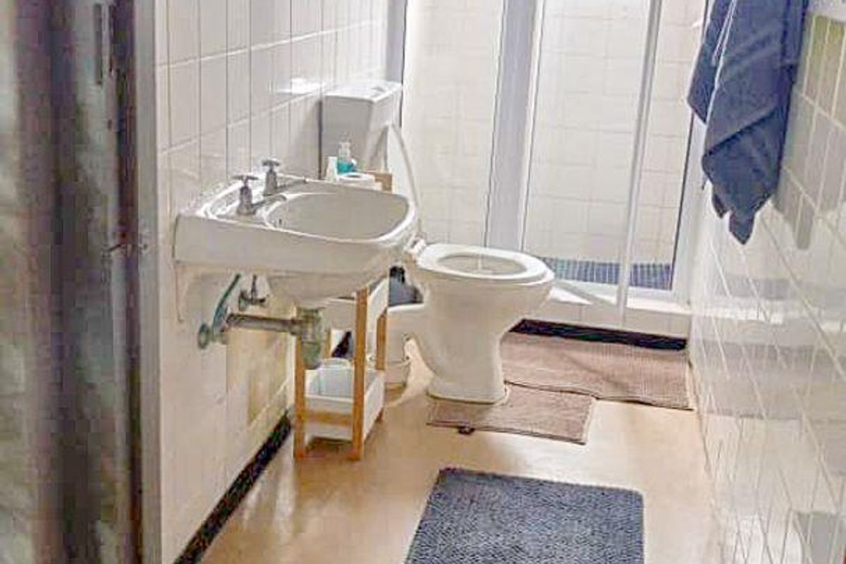 A functional bathroom featuring a wall-mounted basin, toilet, and a separate shower enclosure with tiled wall finishes.