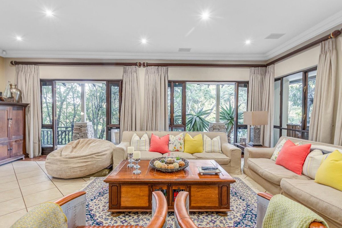 Spacious living room featuring large glass sliding doors that open onto a covered patio, recessed ceiling lighting, and neutral tiled flooring.