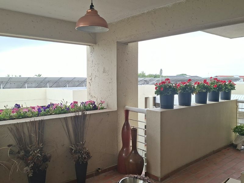 Covered balcony featuring terracotta flooring, textured walls, and a built-in masonry balustrade, offering an outdoor space suitable for relaxation.