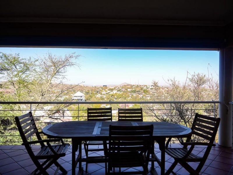 Covered balcony featuring tiled flooring and a metal balustrade, offering expansive elevated views of the surrounding landscape.
