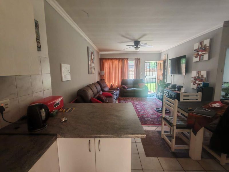 Open plan living and dining area featuring tiled floors, a ceiling fan, and direct access to the rear garden through a security gate.