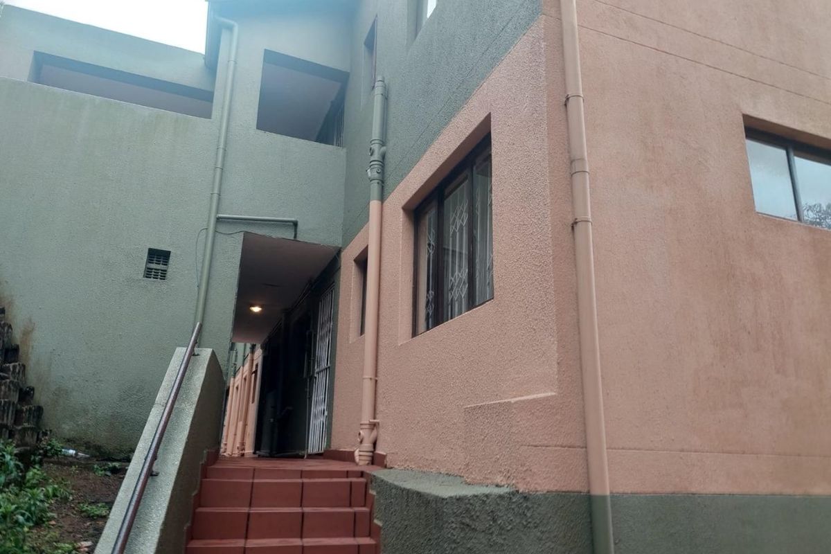 Exterior view of the apartment building featuring a tiled staircase, metal handrails, and security gates at the entrance.
