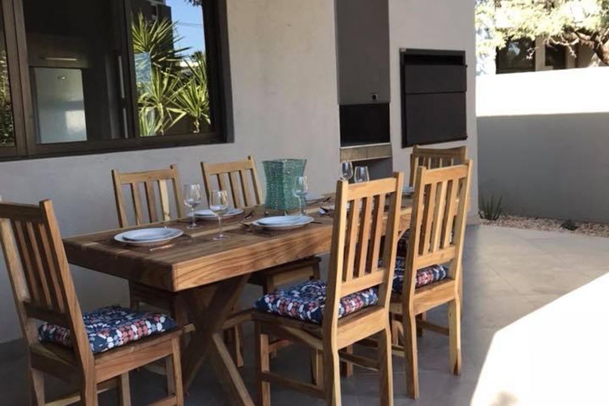 A covered patio area featuring tiled flooring and a built-in braai, perfect for outdoor dining and entertaining.