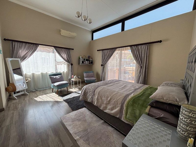 Spacious bedroom featuring laminate flooring, split-system air conditioning, and large sliding glass doors that provide ample natural light and access to the outdoors.