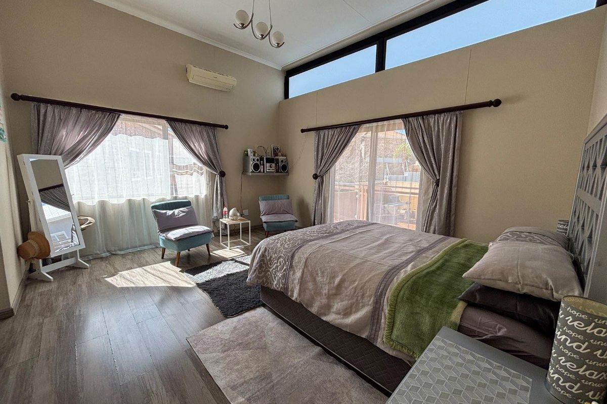 Spacious bedroom featuring laminate flooring, split-system air conditioning, and large sliding glass doors that provide ample natural light and access to the outdoors.