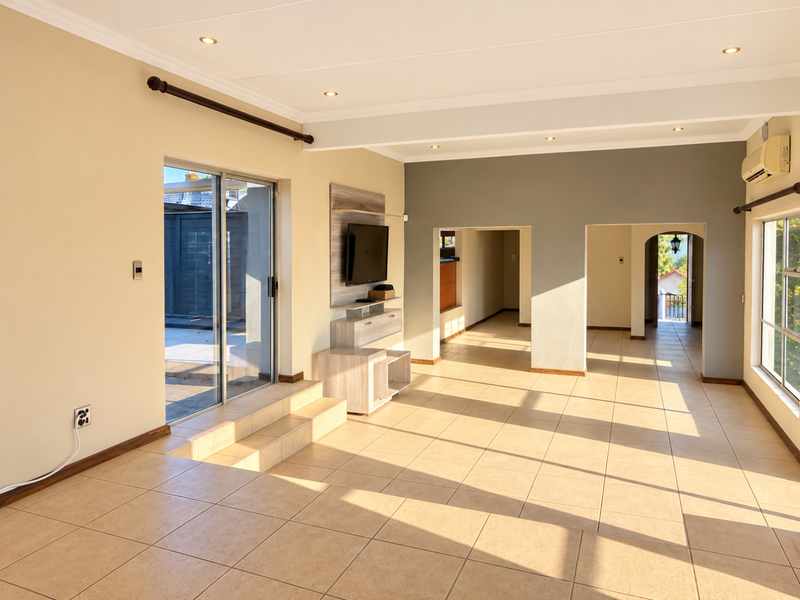 Spacious, sunlit living area featuring neutral tiled flooring, recessed lighting, and direct access to an outdoor patio through a sliding glass door.