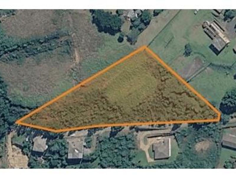 An aerial view of a vacant residential plot of land, highlighting the property boundaries and surrounding landscape.
