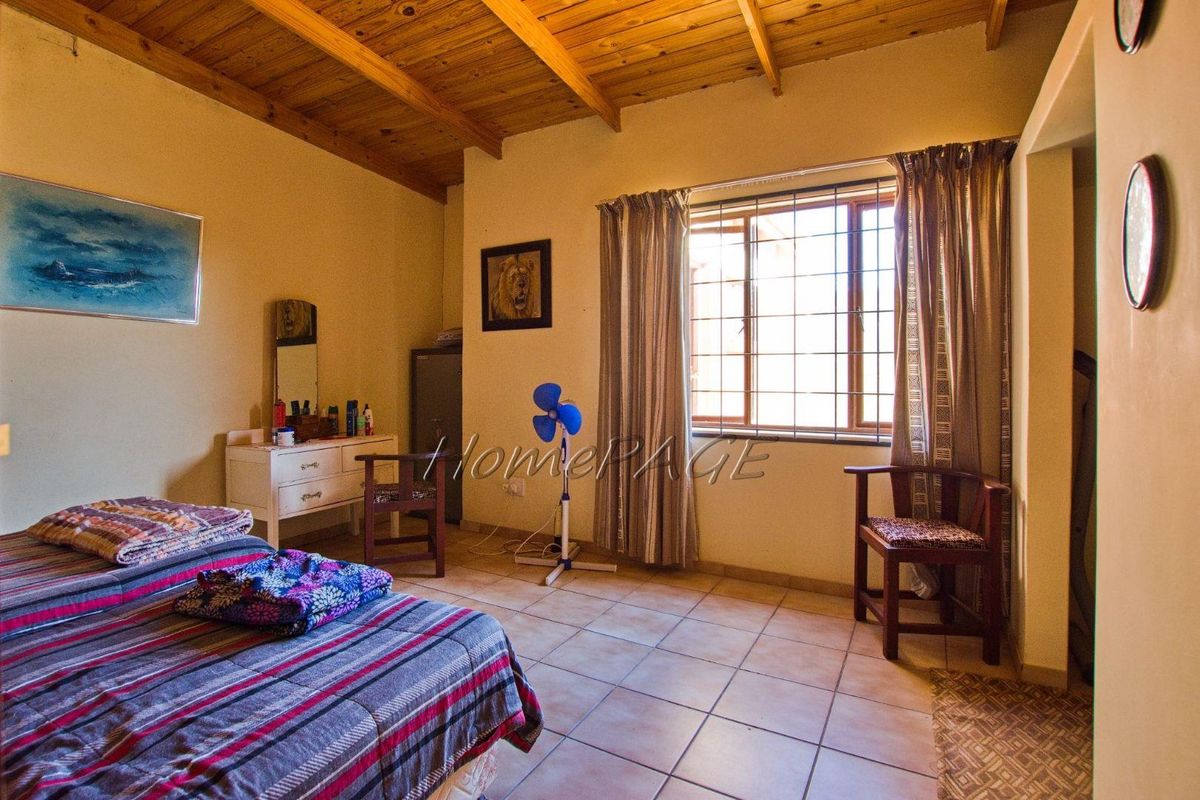 A bedroom featuring exposed timber ceiling beams, tiled flooring, and a window with security bars.