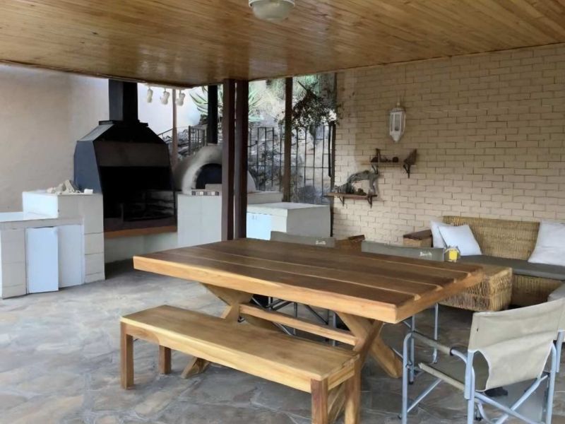 Covered outdoor patio featuring a built-in braai, pizza oven, stone flooring, and a timber ceiling, ideal for alfresco dining and entertaining.