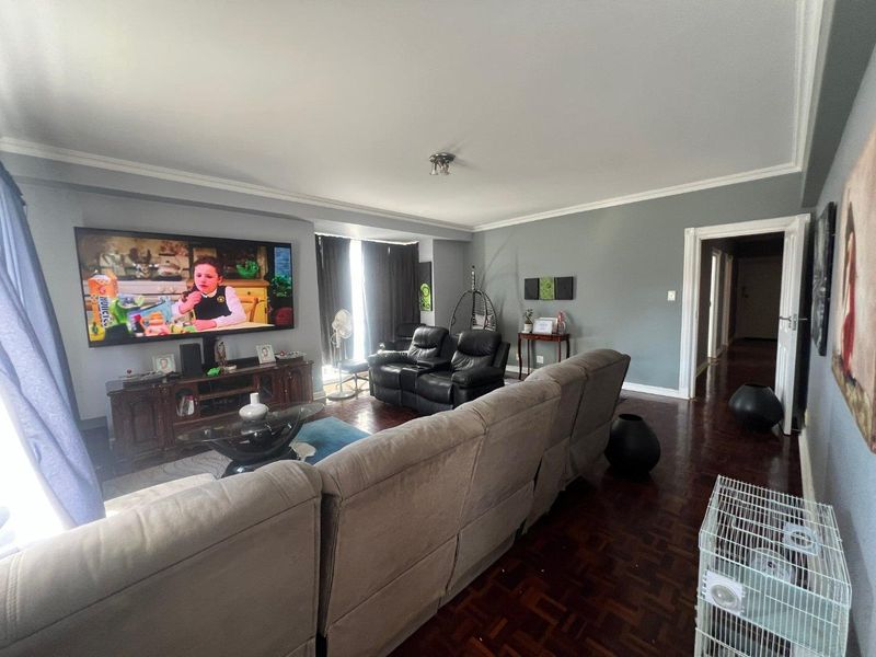 Spacious living room featuring classic parquet flooring, crown molding, and a large window area, providing a comfortable and well-defined lounge space.