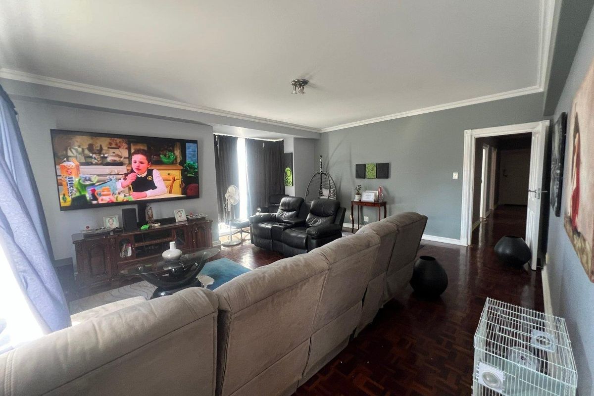 Spacious living room featuring classic parquet flooring, crown molding, and a large window area, providing a comfortable and well-defined lounge space.