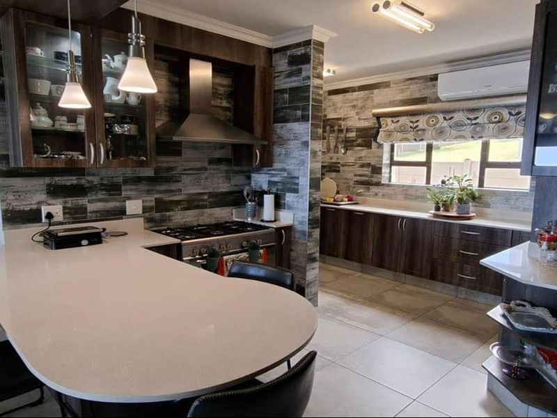 Modern kitchen featuring dark wood cabinetry, quartz countertops, a gas hob with extractor fan, and tiled flooring, offering a functional and stylish cooking space.