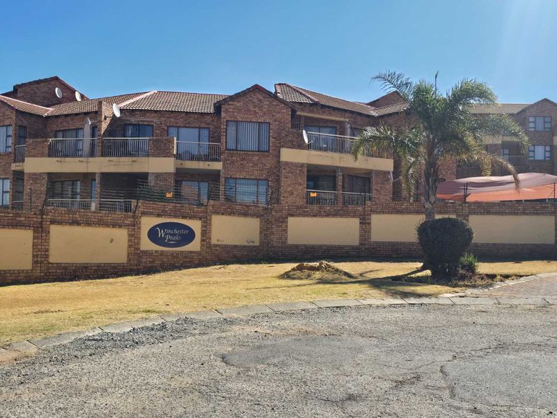 Front exterior view of the Winchester Peaks townhouse complex, featuring face brick architecture, private balconies, and secure perimeter walling.
