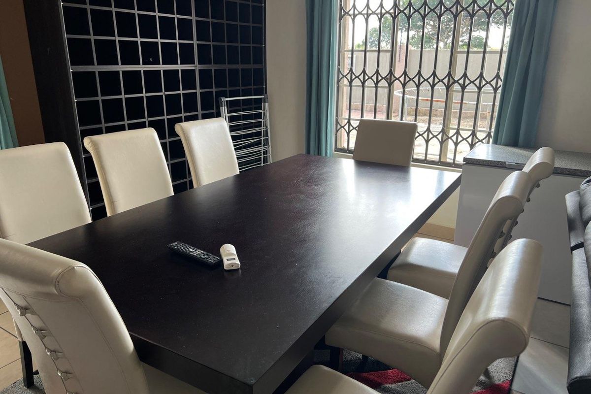 A dining area featuring a built-in dark shelving unit and a window secured with metal security bars.