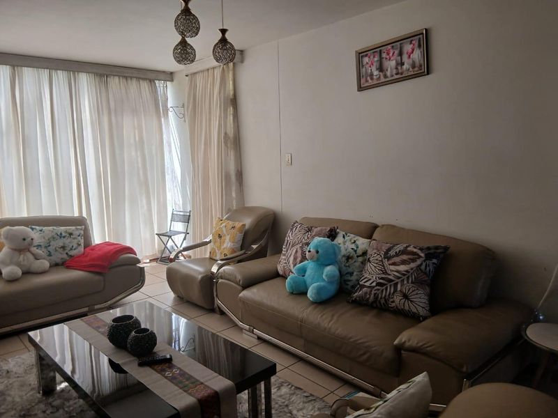 A comfortable living room featuring tiled flooring, pendant lighting, and a large sliding glass door that provides access to the outdoor area.