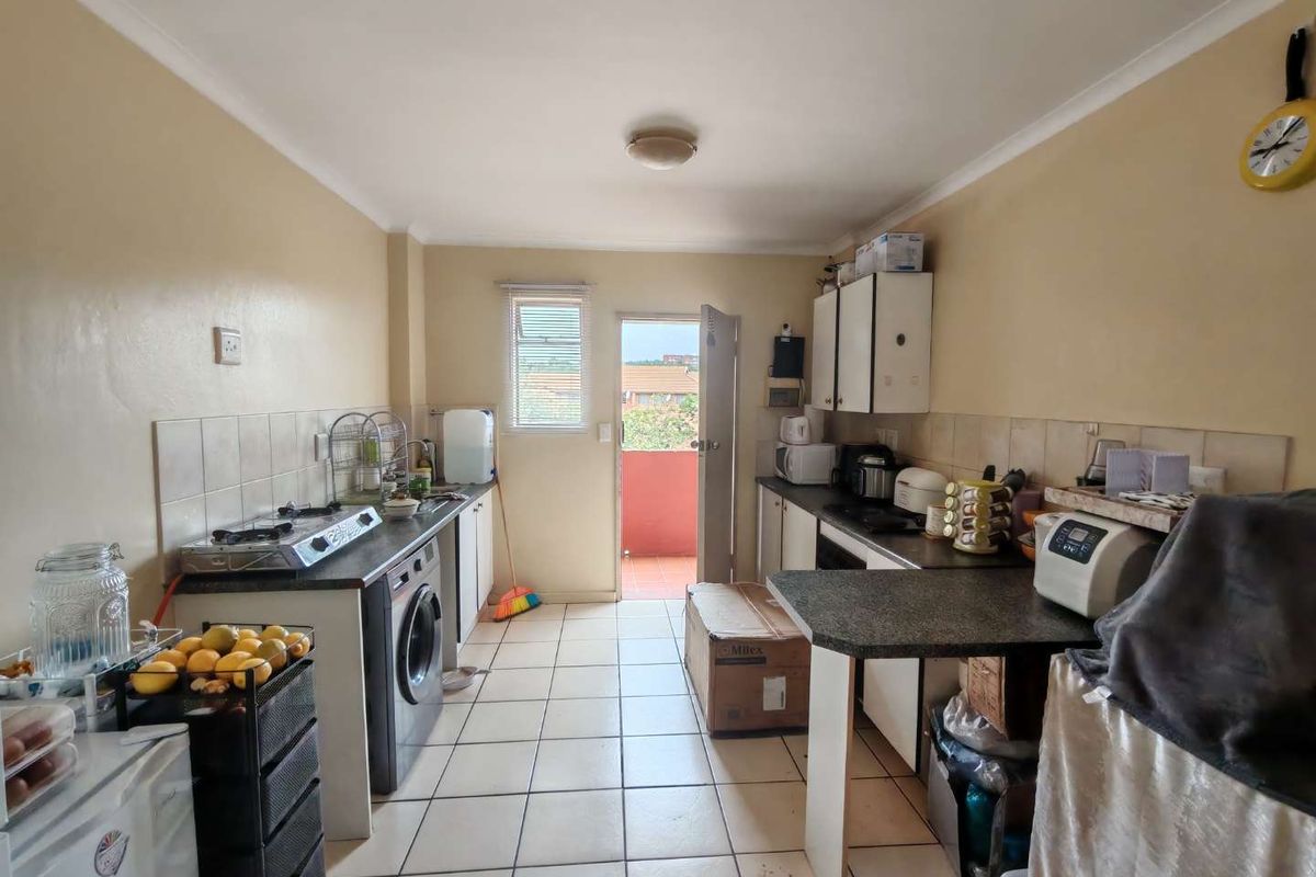 A functional kitchen featuring tiled flooring, built-in cabinetry, and direct access to an outdoor balcony area.