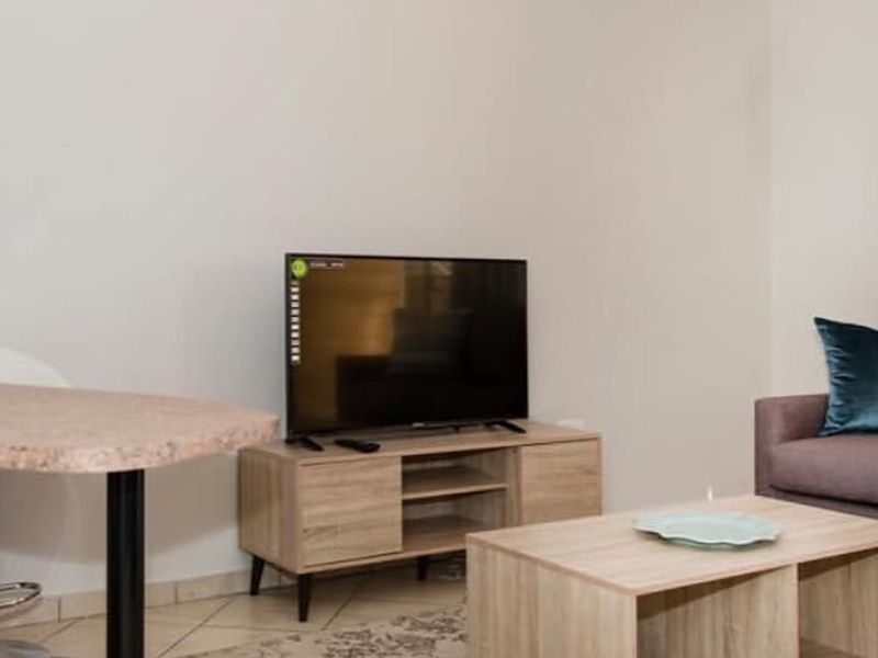 A living room area featuring neutral wall tones and tiled flooring, providing a functional and well-lit space for relaxation.