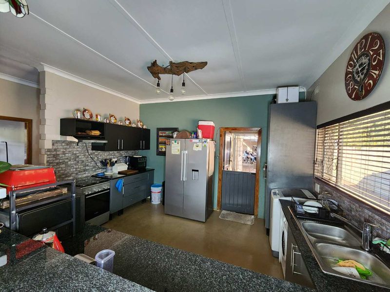 A functional kitchen featuring dark cabinetry, granite countertops, a double basin sink, and a stable door leading to the exterior.