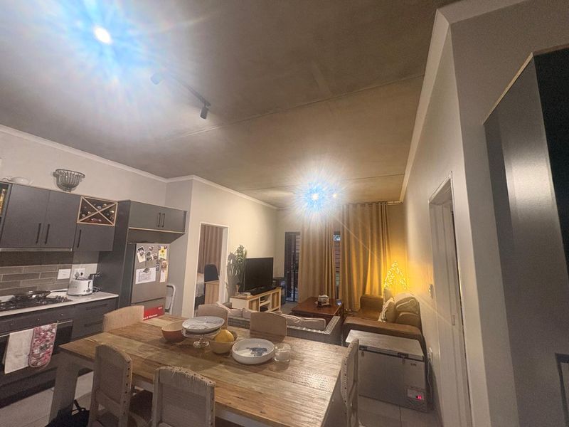 Open-plan living area featuring a modern kitchen with built-in cabinetry, gas hob, and extractor fan, flowing into a comfortable lounge and dining space.