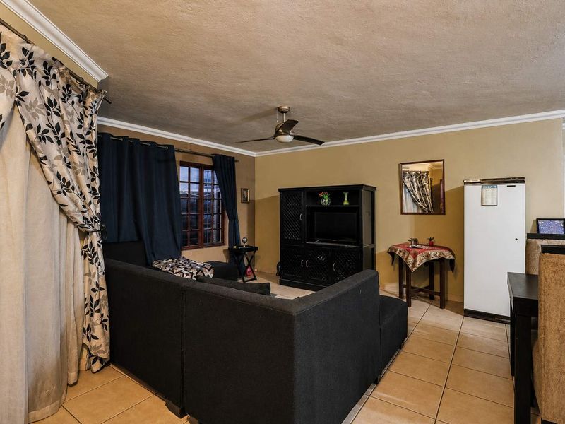 A living room area featuring tiled flooring, a ceiling fan, and neutral wall tones, providing a functional space for relaxation.