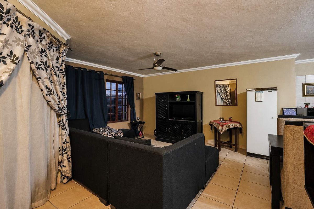 A living room area featuring tiled flooring, a ceiling fan, and neutral wall tones, providing a functional space for relaxation.