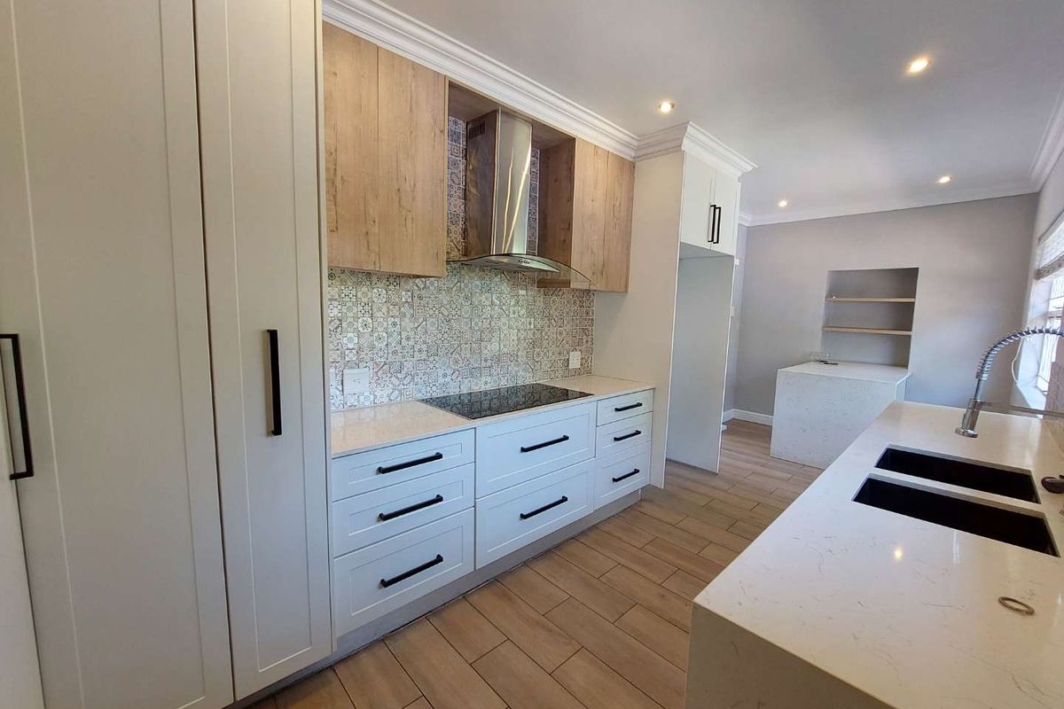Modern kitchen featuring white and wood-tone cabinetry, quartz countertops, patterned tile backsplash, integrated hob, and high-quality finishes throughout.