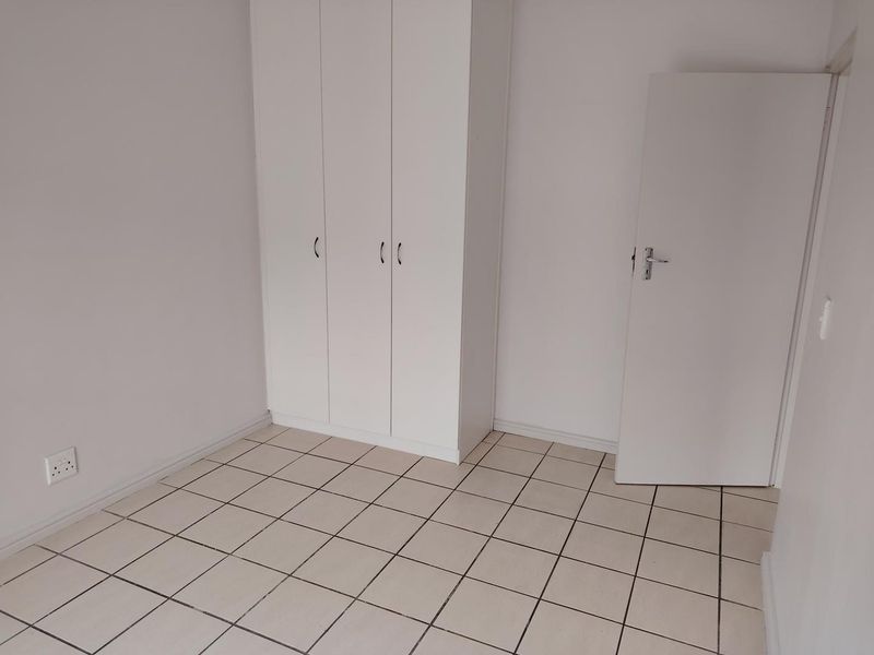 A clean, empty bedroom featuring neutral tiled flooring and white built-in cupboards, providing a blank canvas for personalization.