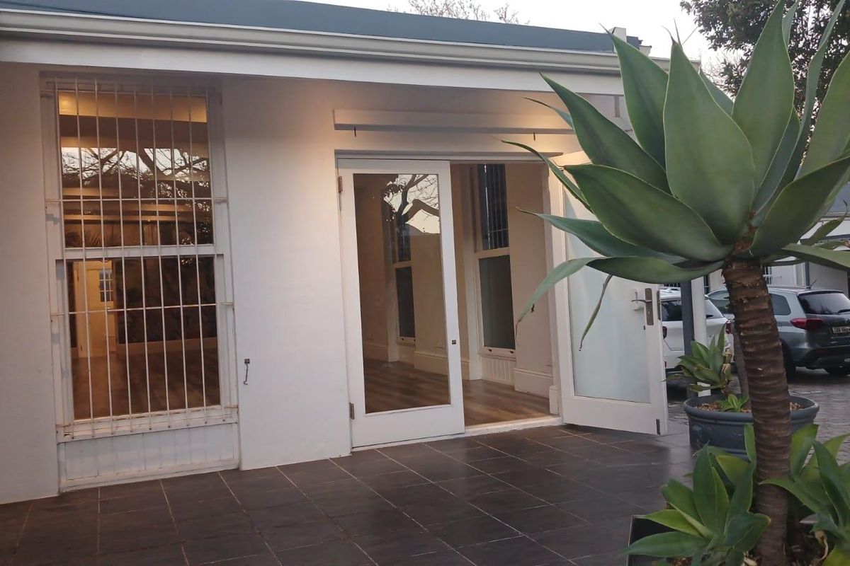 A paved rear patio area featuring double glass doors providing access to the office interior, complemented by a clean tiled outdoor space.