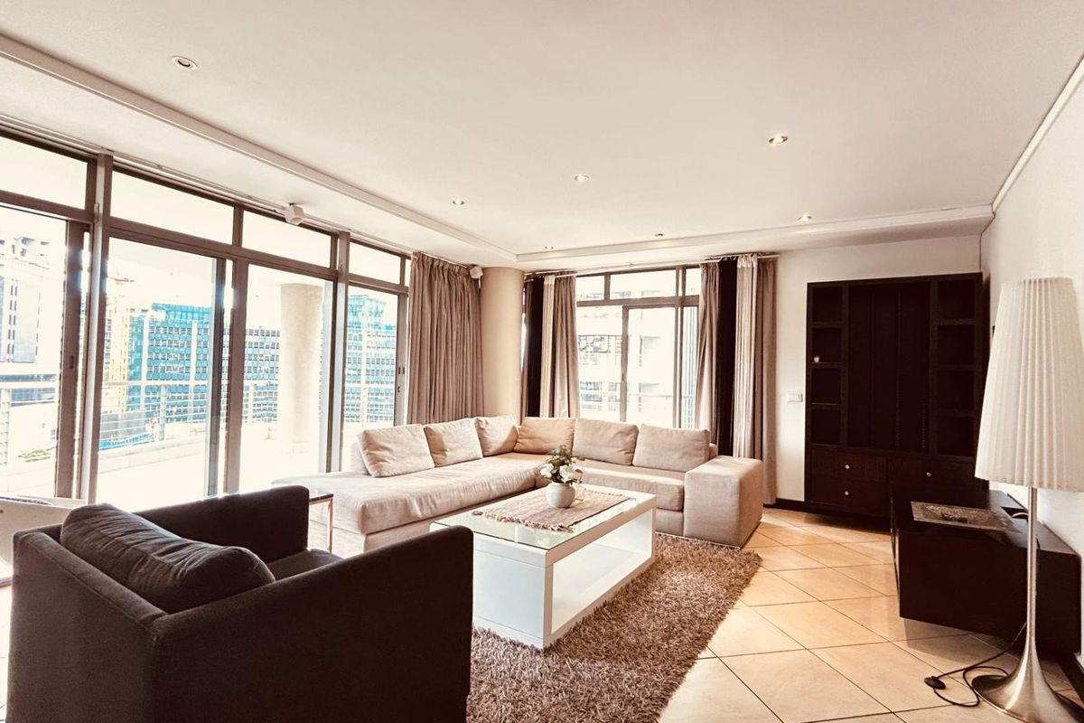 Spacious living room featuring large sliding glass doors, tiled flooring, recessed lighting, and a built-in shelving unit, offering ample natural light and city views.