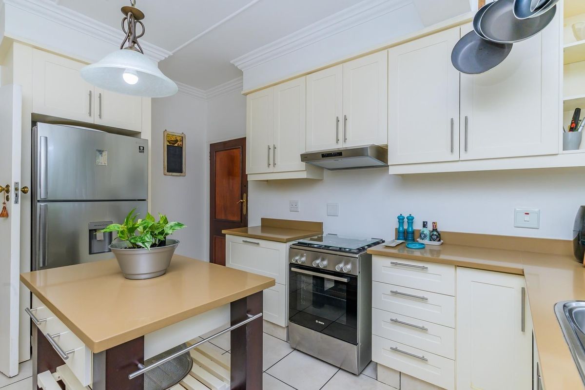 A well-maintained kitchen featuring cream cabinetry, stone countertops, a central island, and a stainless steel oven with an integrated extractor fan.