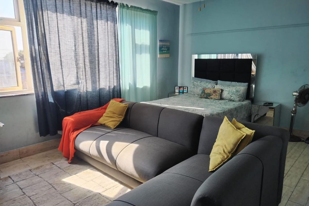 A bedroom featuring tiled flooring and a large window, providing natural light to the space.