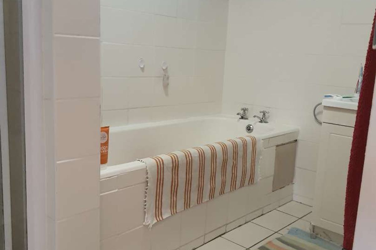A functional bathroom featuring a built-in bathtub with tiled splashback and a separate shower enclosure.
