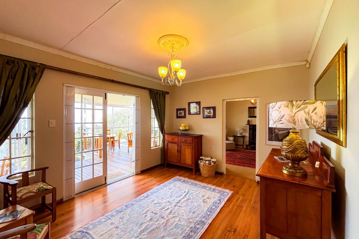 A well-maintained living room featuring polished hardwood floors, a decorative ceiling rose, and french doors providing access to an outdoor patio area.