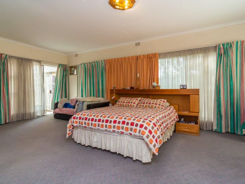 Spacious bedroom featuring carpeted flooring, a built-in headboard, and direct access to an outdoor area through a sliding glass door.