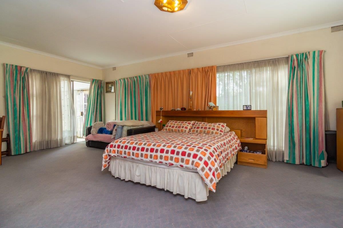 Spacious bedroom featuring carpeted flooring, a built-in headboard, and direct access to an outdoor area through a sliding glass door.