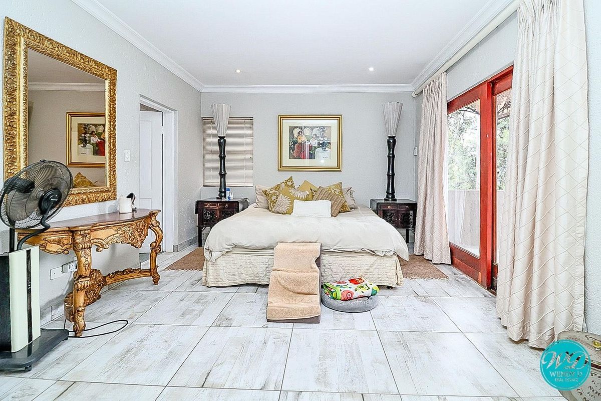 Spacious bedroom featuring light-toned tiled flooring, recessed ceiling lighting, and large sliding glass doors providing access to an outdoor area.