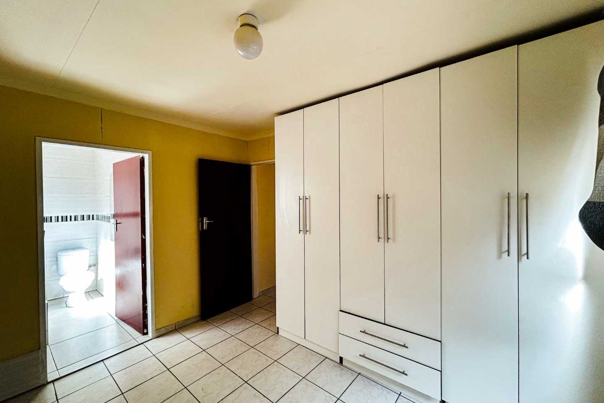A bedroom featuring built-in cupboards, tiled flooring, and direct access to an en-suite bathroom.