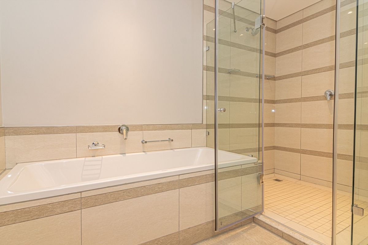 Modern bathroom featuring a built-in bathtub and a separate glass-enclosed walk-in shower with neutral tiled finishes.