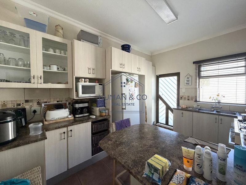 Functional kitchen featuring laminate cabinetry, ample counter space, a double basin sink, and a built-in microwave with direct access to the exterior.
