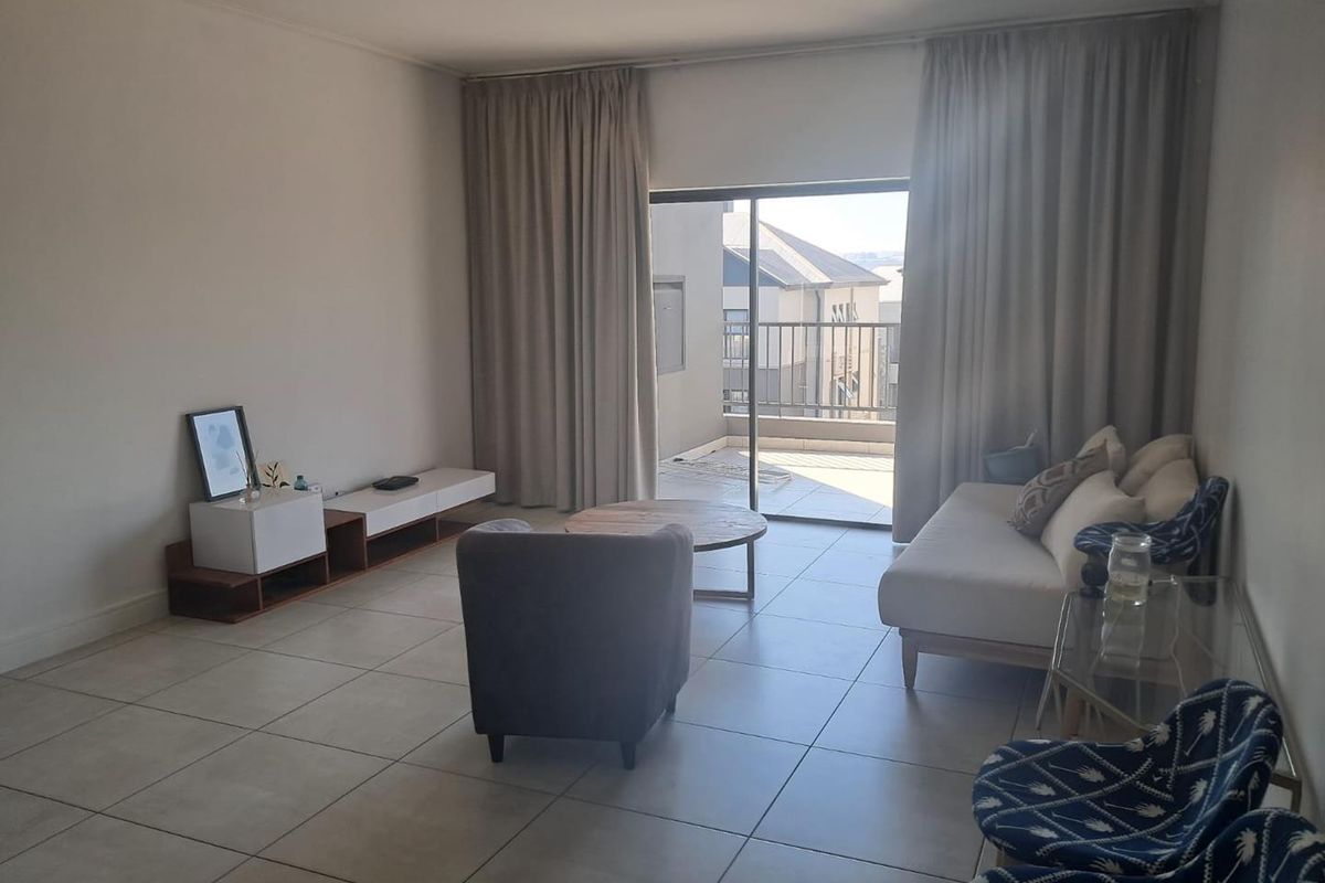 Spacious living room featuring neutral tiled flooring and large sliding glass doors that provide natural light and direct access to the balcony.