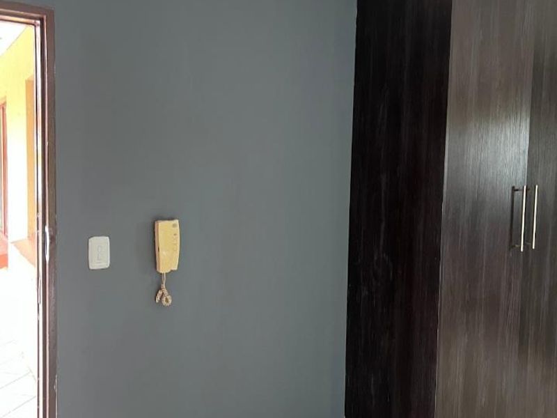 A bedroom featuring dark grey walls, tiled flooring, and a built-in dark wood wardrobe with an integrated intercom system.