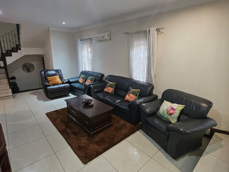 Spacious living room featuring tiled flooring, recessed lighting, a split-system air conditioner, and an internal staircase with a wrought iron balustrade.