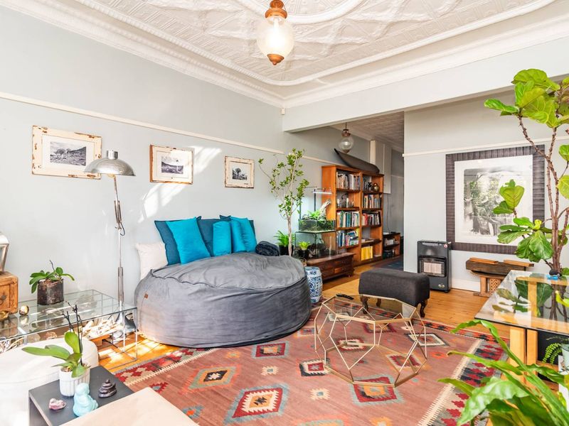 A character-filled living room featuring original ornate pressed metal ceilings, timber flooring, and classic picture rails, offering a warm and inviting atmosphere.