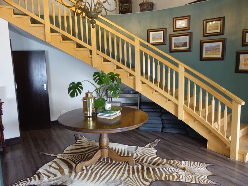An inviting entrance hall featuring a prominent wooden staircase with a matching balustrade and modern laminate flooring.