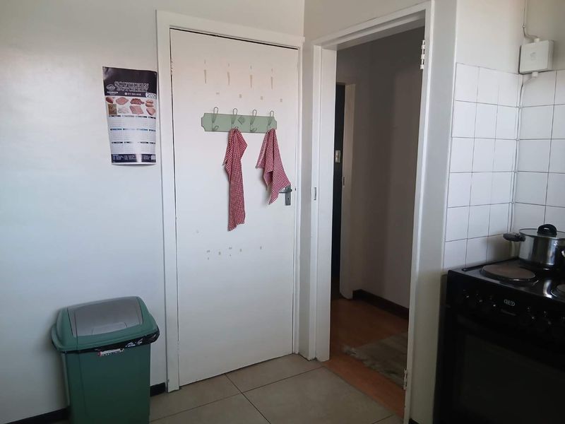 A functional kitchen area featuring tiled splashbacks, an electric stove, and tiled flooring, providing a practical space for meal preparation.