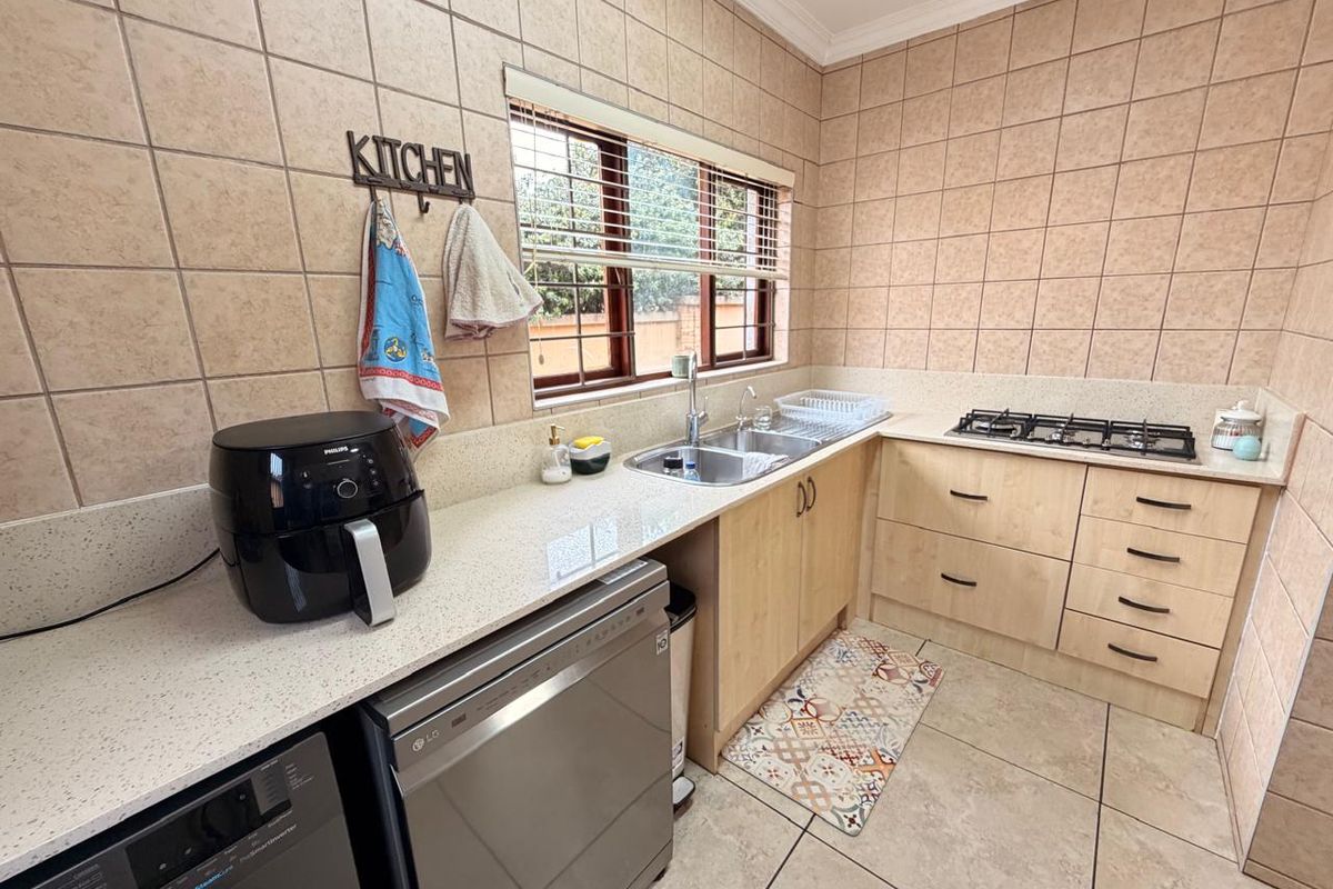 Functional kitchen featuring light wood cabinetry, stone countertops, a gas hob, and full-height wall tiling.