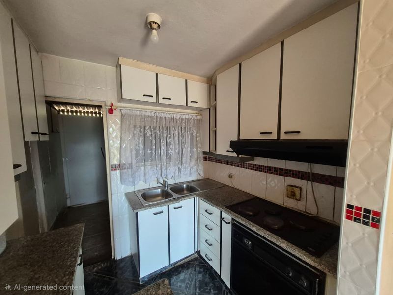 A dated kitchen featuring built-in cabinetry, granite countertops, a double basin sink, and integrated cooking appliances, offering potential for a modern renovation.