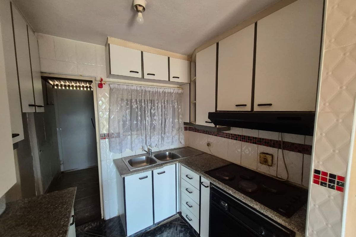 A dated kitchen featuring built-in cabinetry, granite countertops, a double basin sink, and integrated cooking appliances, offering potential for a modern renovation.