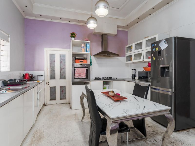 Kitchen featuring built-in oven, gas hob, extractor fan, and cabinetry. The space requires cosmetic updates to the flooring and wall finishes.